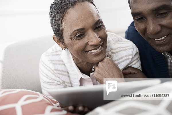 Ein Paar  Mann und Frau  auf dem Bauch liegend  teilen sich ein digitales Tablett.