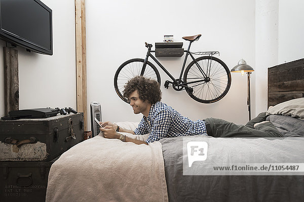 Loft living. A bicycle hanging on a wall. A man using a digital tablet.