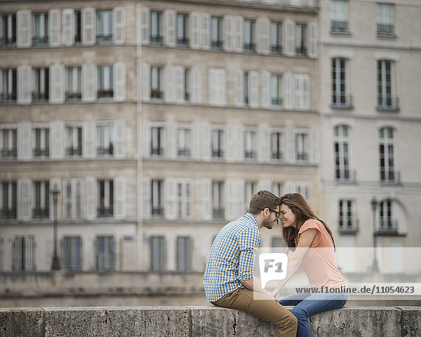Ein Paar  Mann und Frau  die auf der Brüstung einer Brücke über die Seine sitzen.