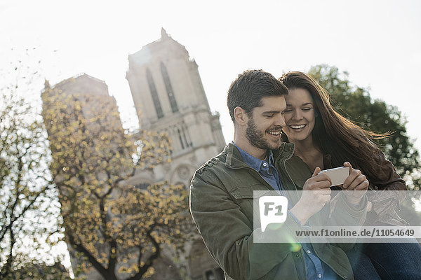 Ein Ehepaar in einer historischen Stadt  das sich ein Smartphone ansieht.