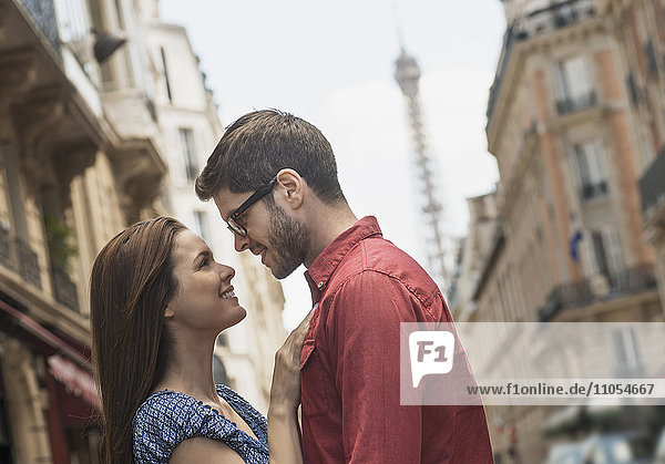 A couple  a man and woman looking into each other's eyes on a city street.