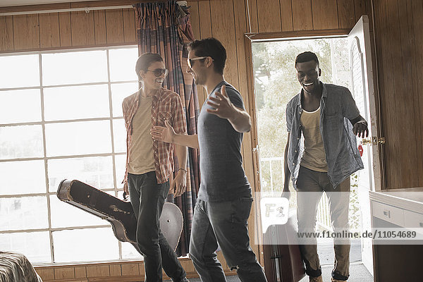 Freunde  drei junge Männer in einem Motelzimmer  mit Koffern und einer Gitarre.