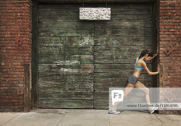 Eine Frau in Laufbekleidung  Korboberteil und Shorts  die ihren Körper streckt und sich auf einen Lauf vorbereitet oder sich nach dem Training abkühlt.