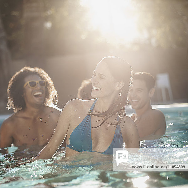 Eine Gruppe junger Männer und Frauen im Schwimmbad am Ende eines heißen Tages.