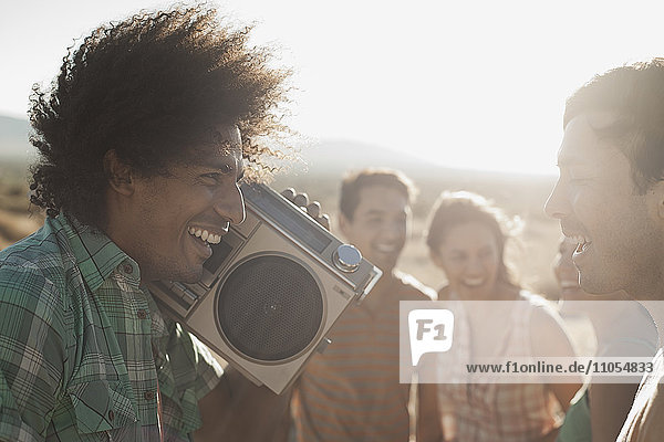 Group of young people  men and women walking on the open road with a boombox.