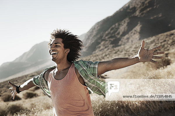A man standing with arms outstretched in a gesture of freedom and excitement  leaning into the breeze.