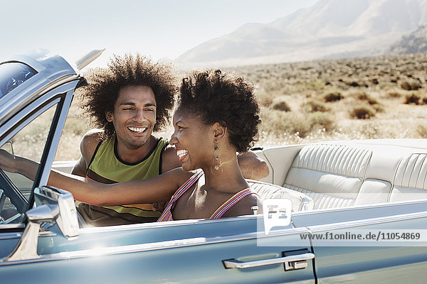 A young couple  man and woman in a pale blue convertible on the open road