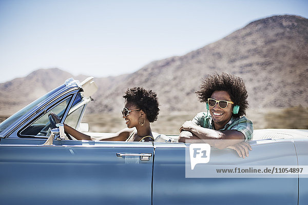 A young couple  man and woman in a pale blue convertible on the open road