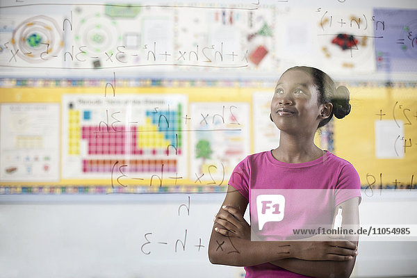 Ein Schüler schreibt mit Stiften Formeln und Gleichungen auf eine durchsichtige Plexiglastafel.