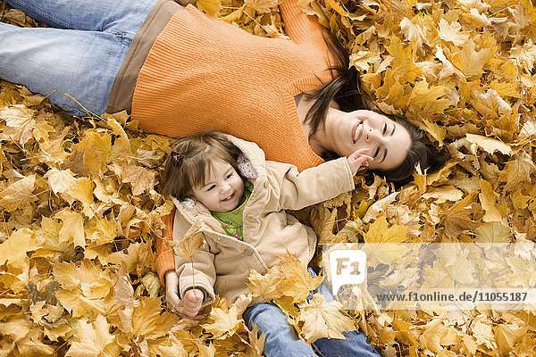 A woman and young child in fallen autumn leaves.