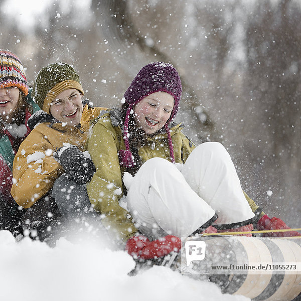 Drei Kinder saßen auf einem Schlitten  der einen Schneehang hinunterrutschte.