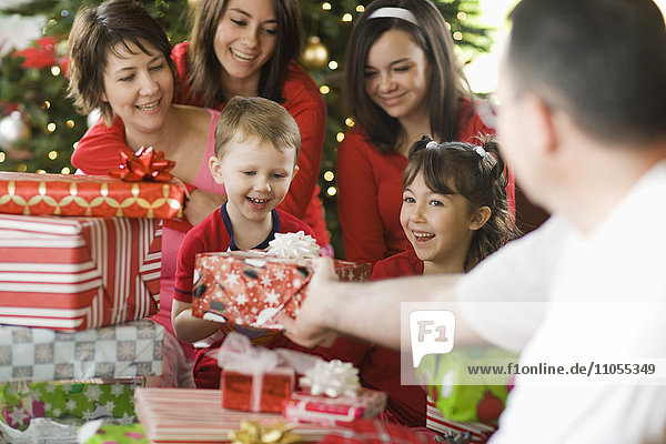 Eine Gruppe von Menschen  Eltern und Kinder  Familie  die am Weihnachtsmorgen Geschenke austauschen.