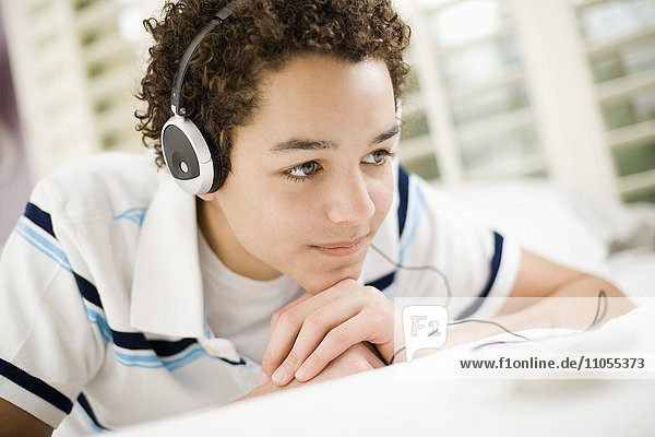 A boy wearing headphones lying on his stomach.