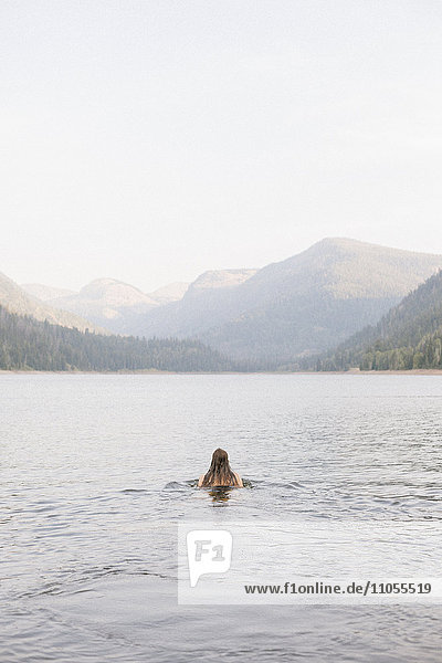 Eine Frau  die im Wasser eines Sees schwimmt.