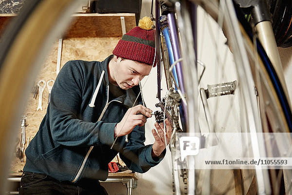 A young man working in a cycle shop  repairing a bicycle.