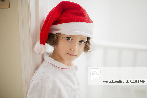 Ein junges Mädchen mit Weihnachtsmannmütze am Weihnachtsmorgen.