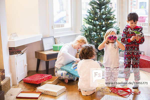 A mother and three children on Christmas morning opening presents.
