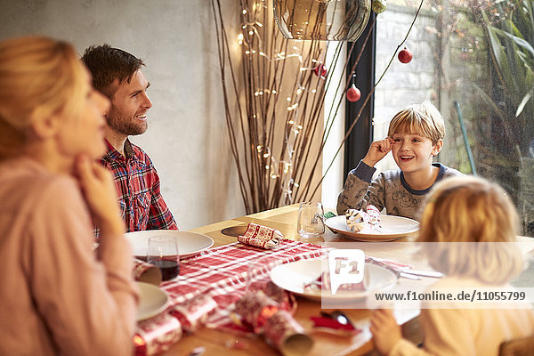 Eine vierköpfige Familie  zwei Erwachsene und zwei Kinder  saß zur Weihnachtszeit um einen Tisch herum und zogen Kekse.