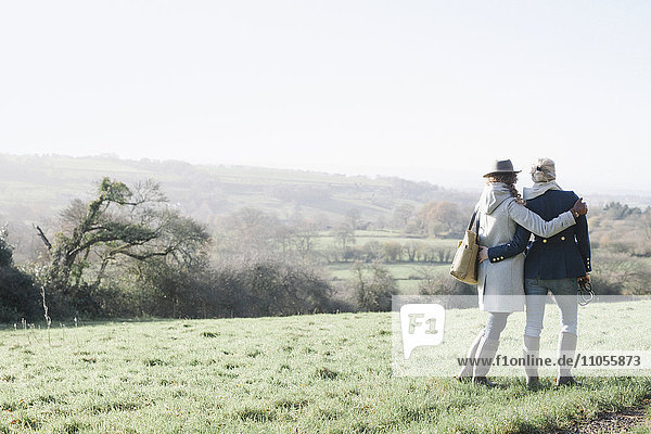 Zwei Frauen nebeneinander auf einem Grashang mit Blick auf die Landschaft von Dorset.