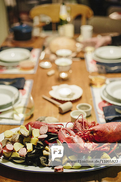 Ein gedeckter Tisch für eine Mahlzeit  eine Meeresfrüchteplatte mit Hummer und Muscheln.