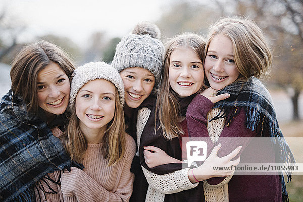 Fünf junge Leute  Mädchen  Freunde in warmen Schals und Wollmützen im Freien.