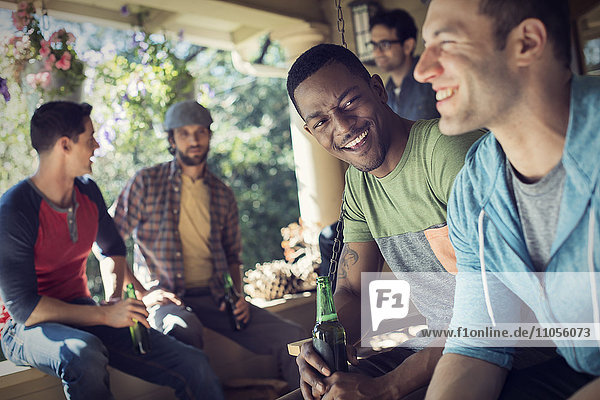 Eine Gruppe von Freunden  Männern und Frauen bei einer Hausparty. Zwei Männer  die zusammen lachen.