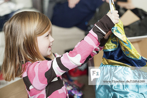 Ein junges Mädchen packt ein Weihnachtsgeschenk aus.