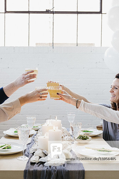 Vier Personen erheben ihre Gläser in einem Trinkspruch bei einer Mahlzeit.