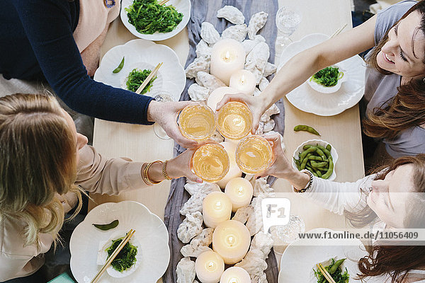 Draufsicht auf vier Personen  die sich eine Mahlzeit teilen  Sushi-Platten und ein gedeckter Tisch für ein Festmahl.