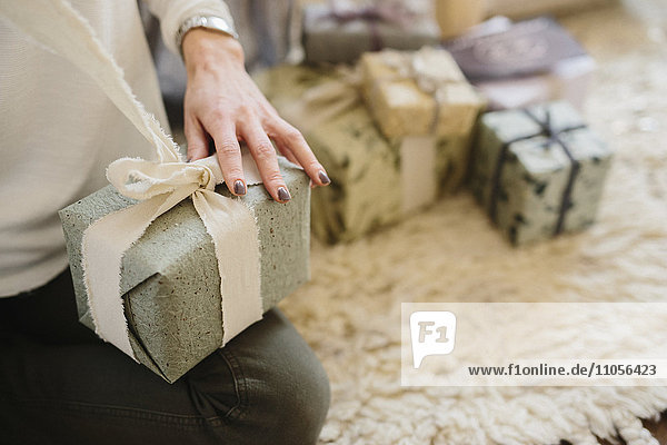 Eine Frau sitzt mit einem Haufen eingepackter Geschenke.