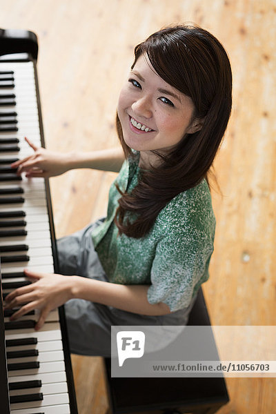 Young woman playing on a grand piano in a rehearsal studio.