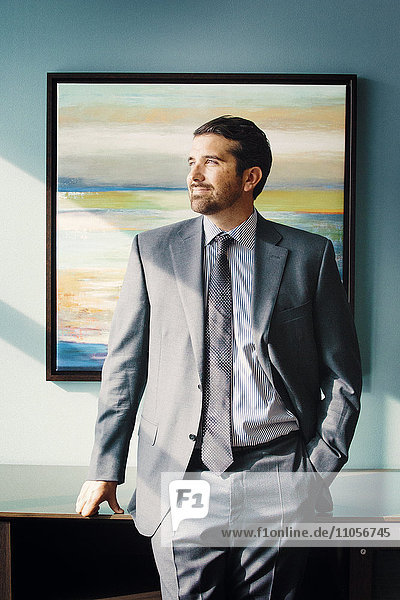 Porträt eines Mannes in einem Anzug  ein Geschäftsmann steht vor einem Kunstwerk.