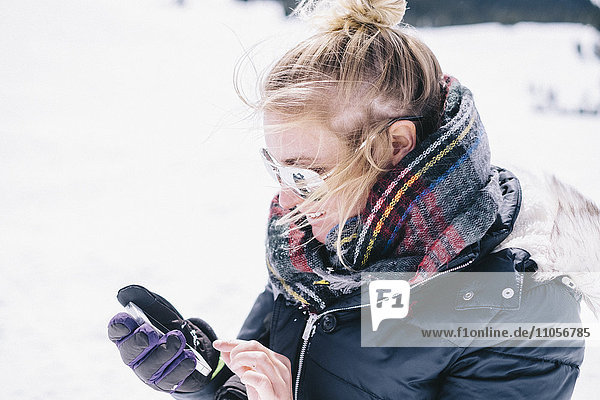 A woman on the ski slopes looking at her smart phone.