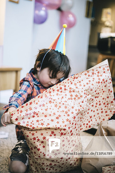 A boy unwrapping presents at a birthday party.