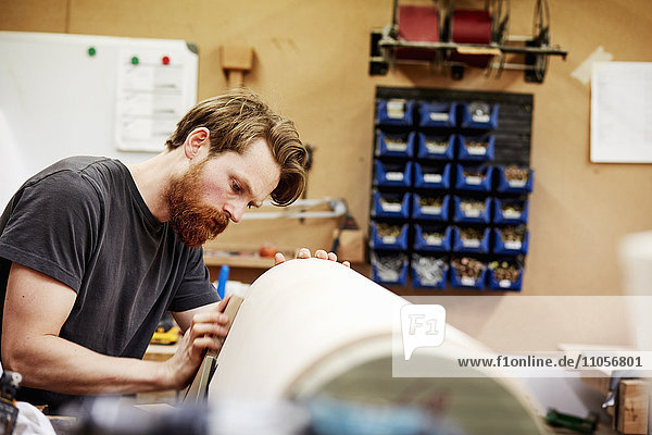 Eine Möbelwerkstatt  die maßgeschneiderte zeitgenössische Möbelstücke unter Verwendung traditioneller Fertigkeiten im modernen Design herstellt. Ein Mann arbeitet an einem gebogenen Holzstück.