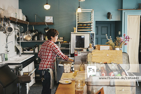 A woman working behind the counter in a coffee shop.