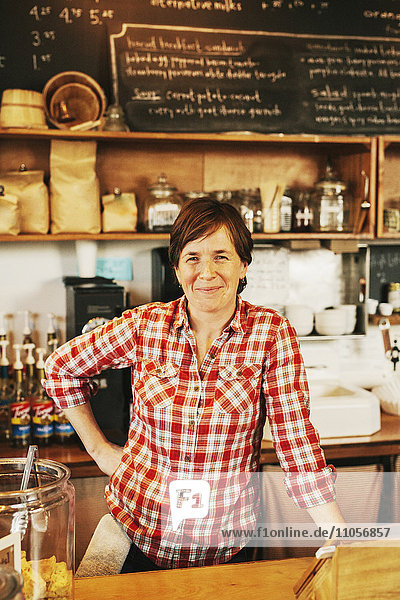 Eine Frau in einem Kaffeehaus hinter der Theke  lächelnd  Geschäftsinhaber.