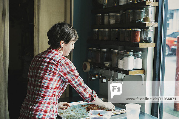 Eine Frau mit einem Tablett mit gekochtem Speck in einer Coffee-Shop-Küche.