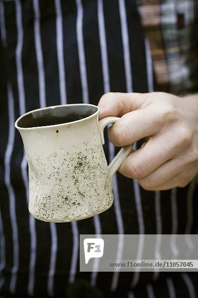 Close up of a chef holding a mug.