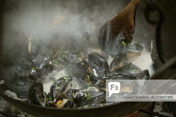 Chef cooking Black Mussels over a barbecue.