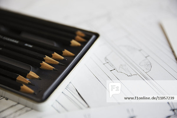 Nahaufnahme von Entwurfszeichnungen für Möbel und ein Tablett mit Bleistiften.