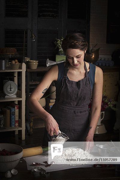 Valentinstag beim Backen  junge Frau steht in einer Küche  bereitet Teig für Kekse zu  gießt Milch aus einer Kanne.