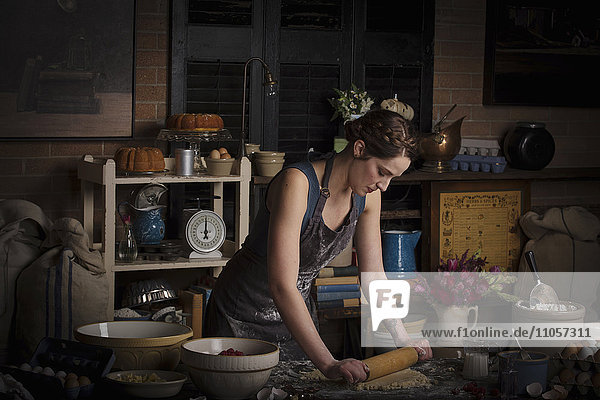 Valentinstag beim Backen  junge Frau steht in einer Küche und bereitet Teig für Kekse vor.