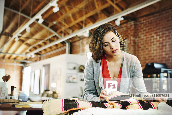 Junge Frau in einem Geschäft  die sich kleine gestreifte Teppiche ansieht.