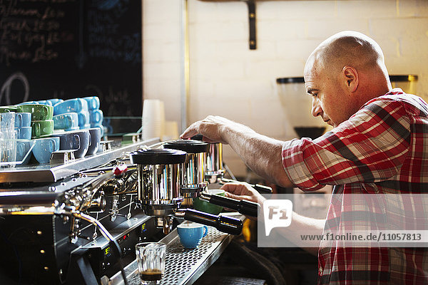 Specialist coffee shop. A man working a coffee machine making coffee.