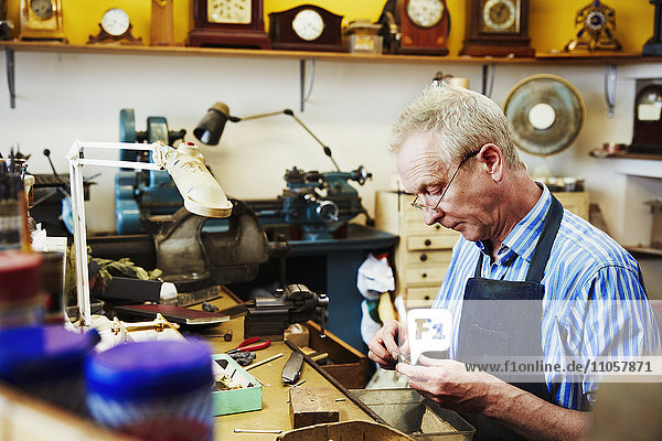 A clock maker busy in his workshop.