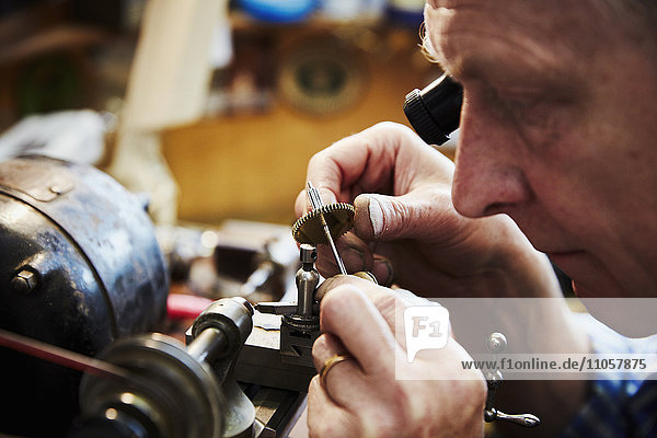 Ein Uhrmacher  der in seiner Werkstatt beschäftigt ist.