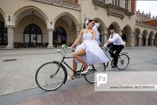 Bride cycling ahead of groom on a bicycle  Krakow  Poland  Europe