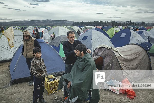 Idomeni refugee camp on the Greek Macedonia border  hairdresser cuts the hair of a migrant man  Idomeni  Central Macedonia  Greece  Europe