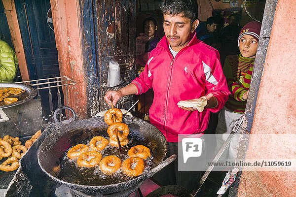 Ein Mann bäckt Donuts in einem großen Wok für das typische nepalesische Frühstück  Tansen  Palpa  Nepal  Asien